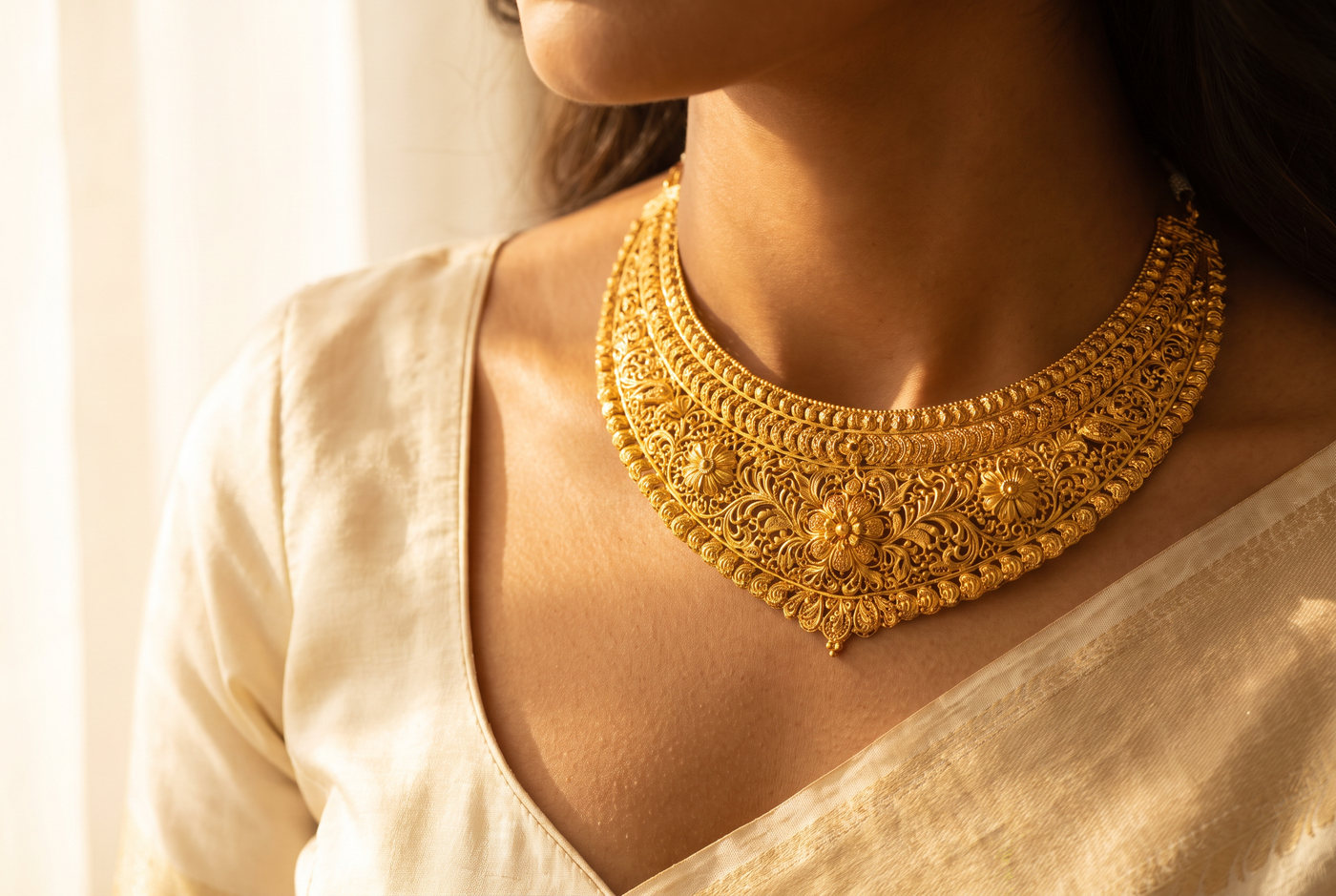 A wide 22 carat gold collar necklace worn at the collarbone