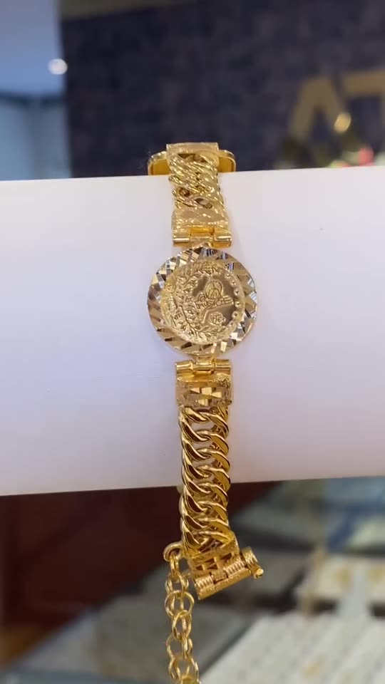 A heavy curb-link 21 carat gold bracelet with an engraved panel on a white roll
