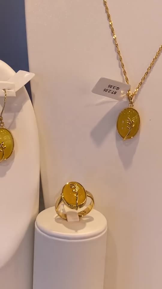 A 21 carat gold set with yellow stones: earrings, pendant and ring on white stands